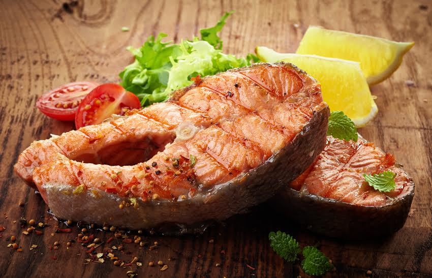 grilled salmon steak slices on wooden cutting board